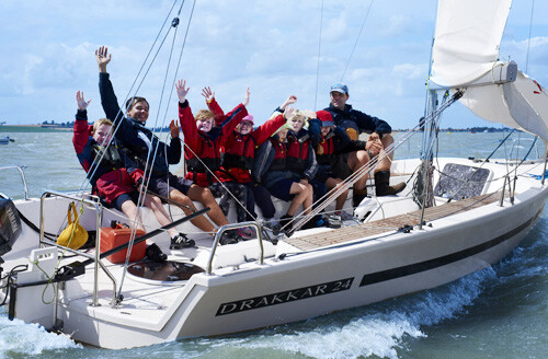 waving group of young people on sailing boat