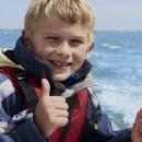 boy giving thumbs up on a dinghy on the sea