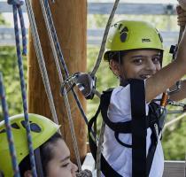 instructor helping boy on high ropes course