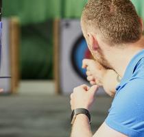 instructor demonstrating how to shoot a bow and arrow