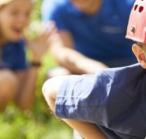 boy with red helmet crawling on a pole