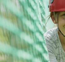 smiling girl in red helmet on cargo net