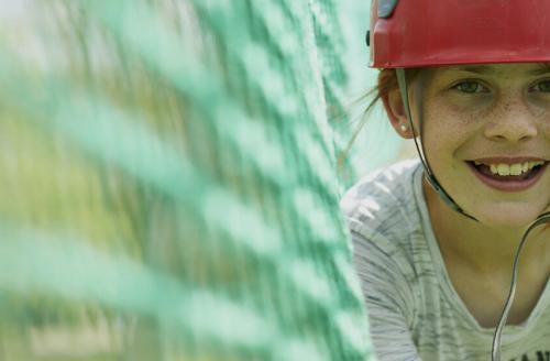 smiling girl in red helmet on cargo net