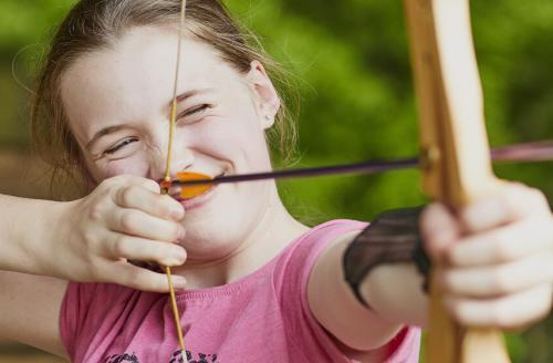 concentrating girl aiming a bow and arrow