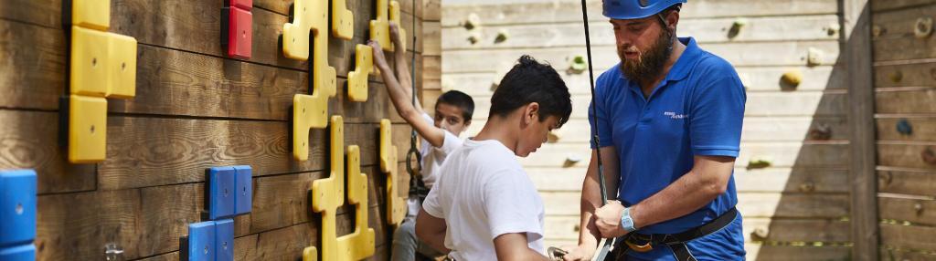 instructor helping boy attach climbing harness