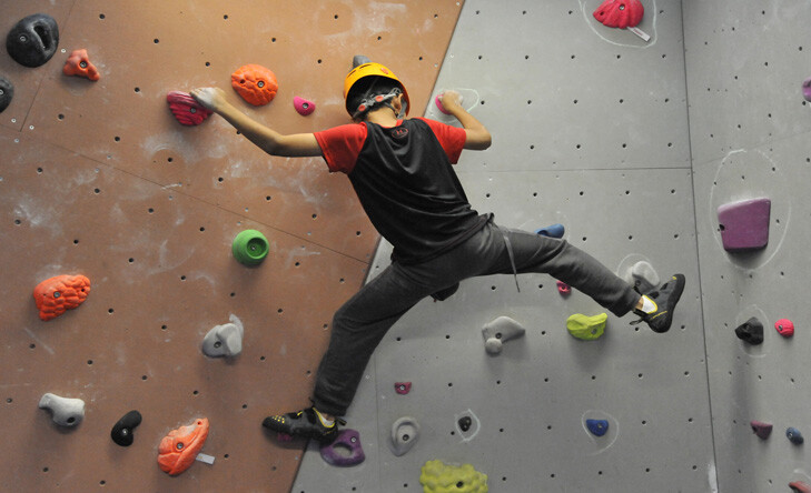 teenage boy climbing on a bouldering wall