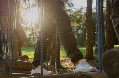 group of adults climbing over wobbly bridge on obstacle course