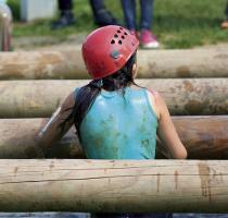 girl climbing over poles on obstacle course