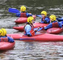 group of young people in red kayaks on the river