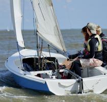 blue wayfarer dinghy with 3 crew on the sea