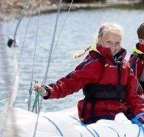 smiling young girl sitting on a sailing boat