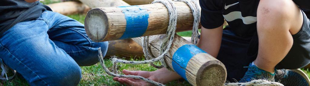 boys tying poles together with ropes