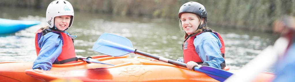 two smiling girls in kayaks