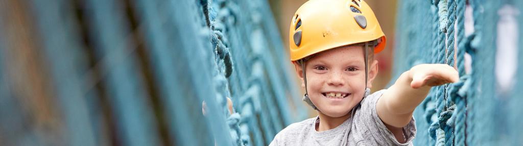 Smiling boy in orange helmet on cargo net