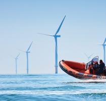 commercial powerboat on calm sea with wind farm in background