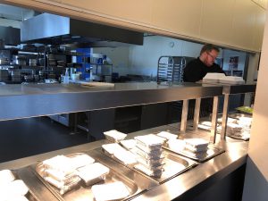 chef working at servery packing meals into containers