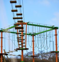 Harlow High Ropes Adventure course empty on a clear blue sky morning. The colourful orange and green metal with exciting obstacles hanging between them.